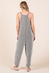 woman wearing a gray and white striped cotton jumpsuit with adjustable straps and tapered legs, shown from the back