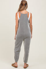 woman wearing a striped maternity jumpsuit with adjustable shoulder straps, showing a relaxed fit and tapered legs