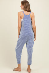 woman wearing a blue and white striped maternity jumpsuit with adjustable straps and side pockets, showing a relaxed fit