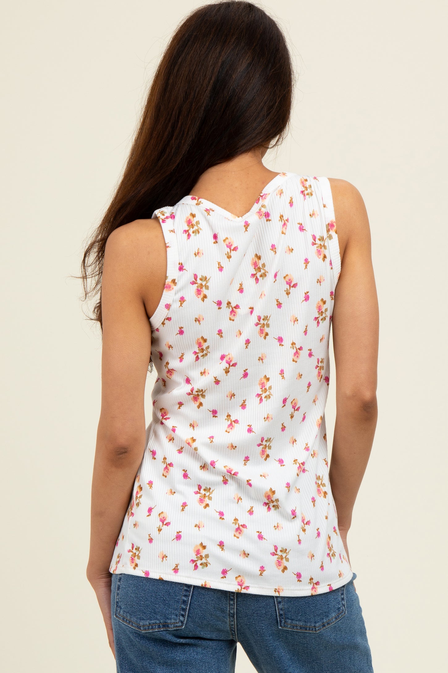 woman wearing a white sleeveless top with a floral print and ribbed texture, viewed from the back