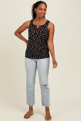 woman wearing a black floral print tank top with a keyhole neckline and light wash distressed jeans