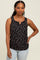 woman wearing a black sleeveless top with a floral print and a button detail, paired with light blue jeans