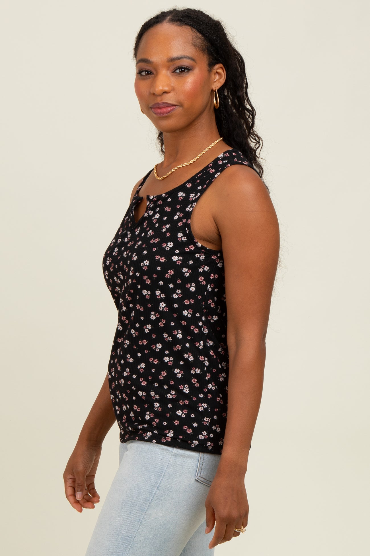 woman wearing a black floral print tank top with a keyhole detail, paired with light blue jeans