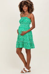 woman wearing a green floral maternity dress with adjustable straps and a baby bump visible