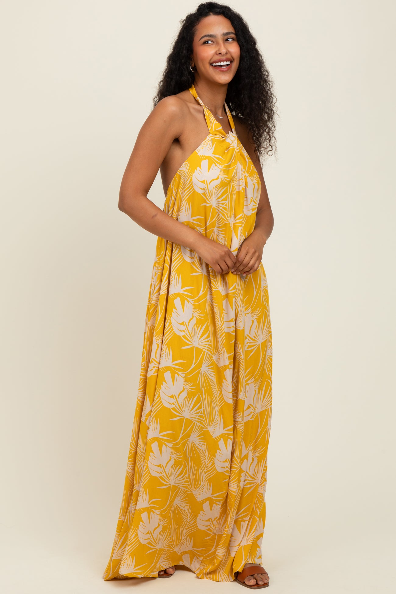 woman wearing a yellow halter neck maxi dress with a floral print