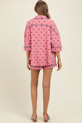 woman wearing a pink and white checkered maternity pajama set with oversized top and shorts, showing a baby bump from the back