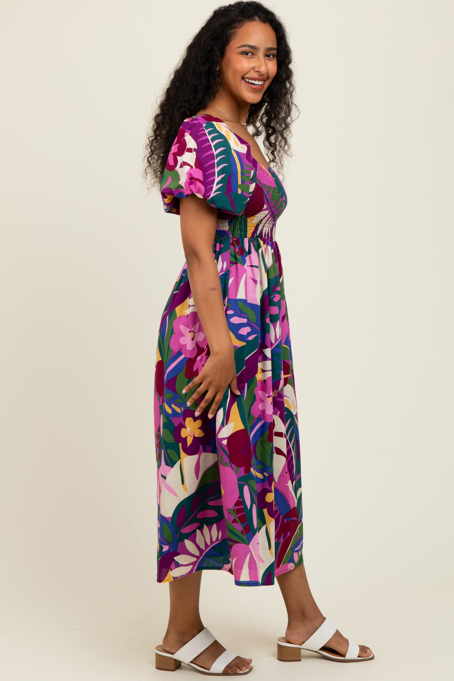 woman wearing a colorful floral print midi dress with puff sleeves and a smocked waist