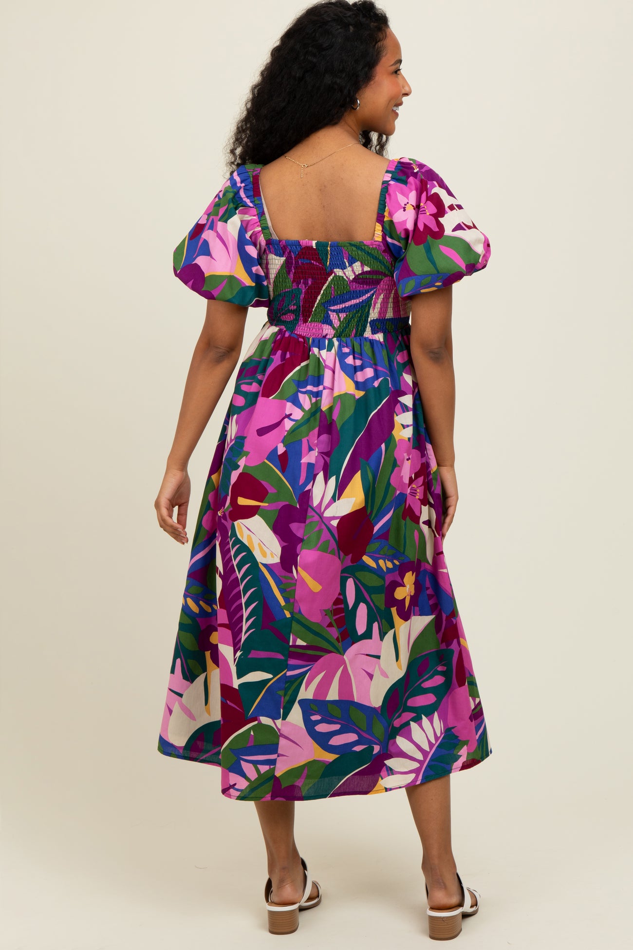 woman wearing a colorful floral print midi dress with puff sleeves and a smocked bodice, showing the back view