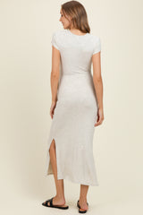 woman wearing a light gray maternity maxi dress with short sleeves and a side slit, viewed from the back