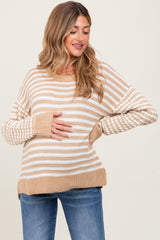 woman wearing a striped beige and cream maternity sweater and holding her baby bump