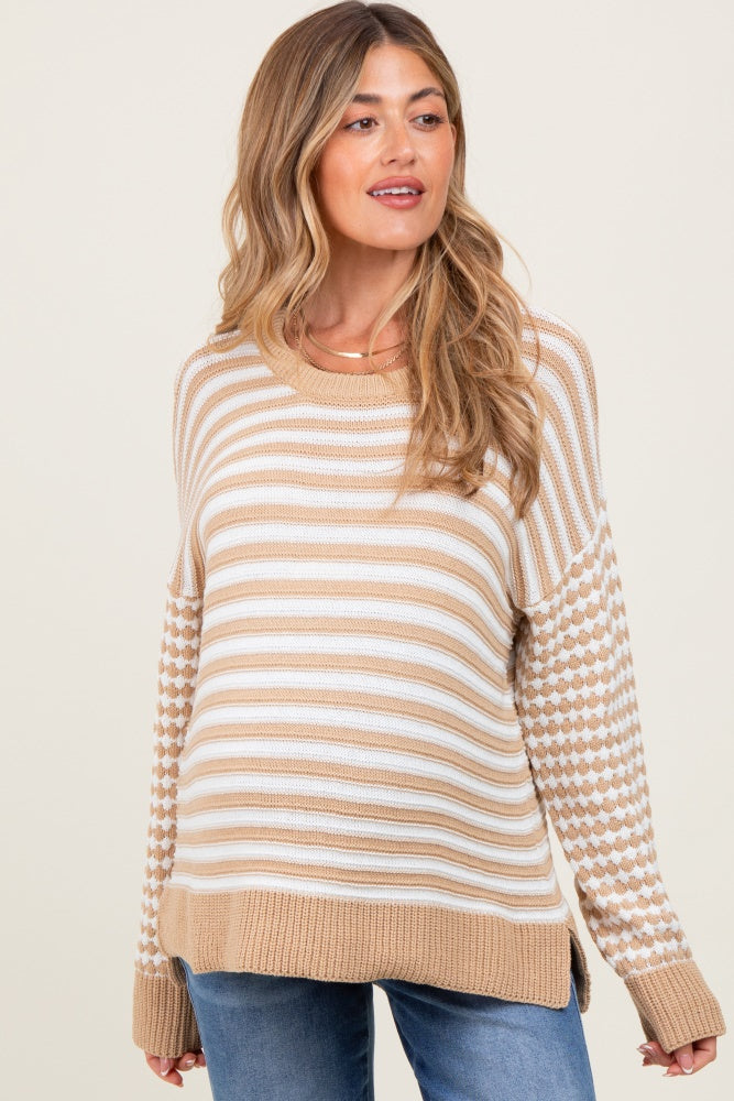 woman wearing a beige and white striped maternity sweater with patterned sleeves and relaxed fit, showcasing her baby bump