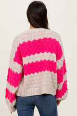 woman wearing a chunky knit sweater with pink and beige stripes, seen from the back, paired with denim jeans