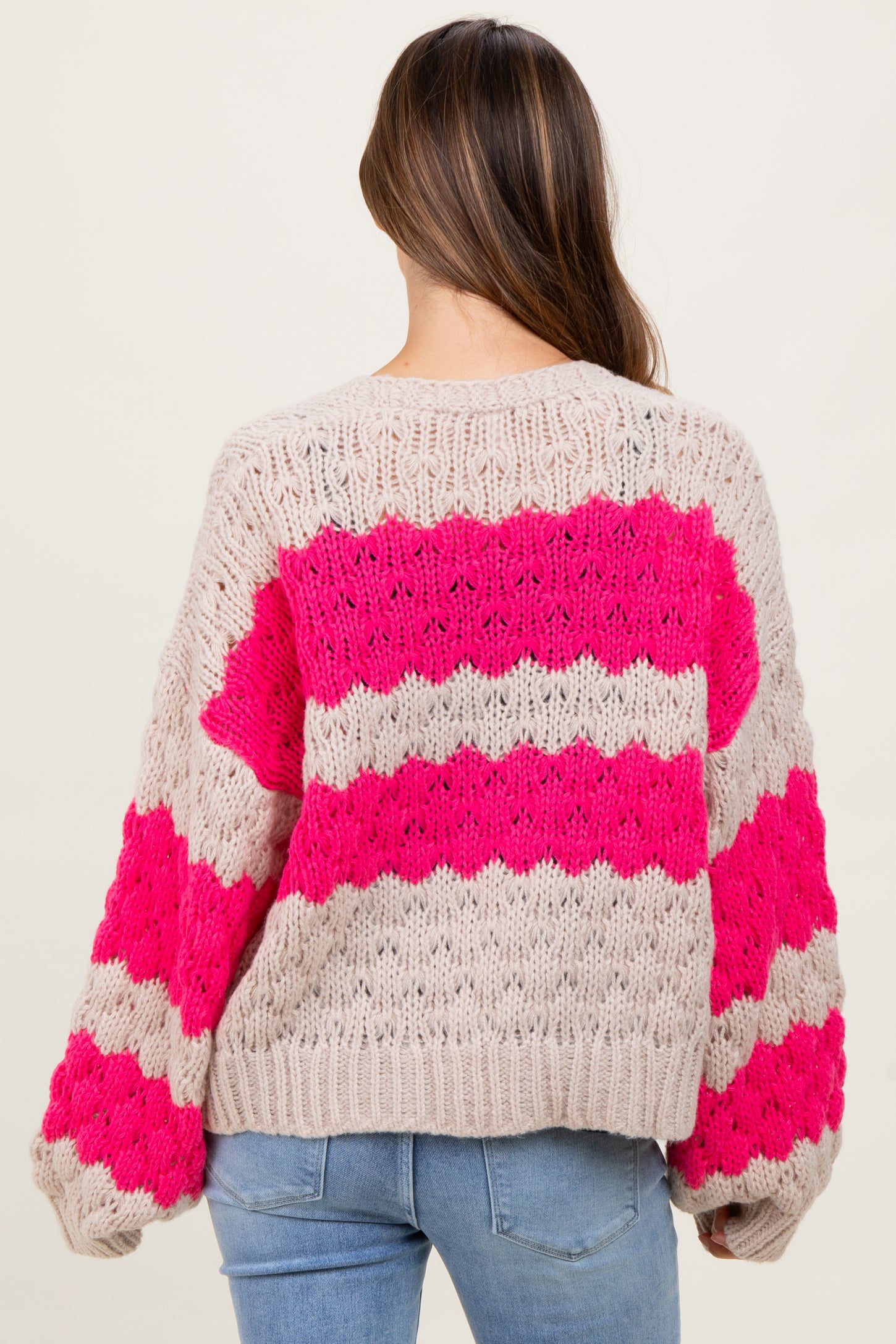 woman wearing a beige and hot pink striped maternity sweater with a relaxed fit and long sleeves