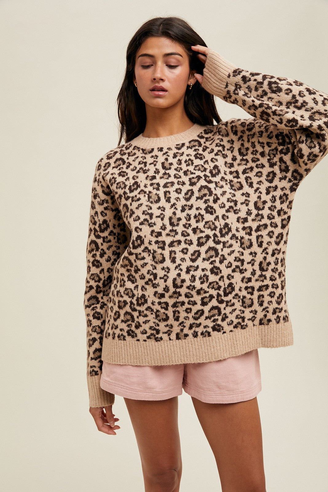 woman wearing a beige leopard print oversized sweater and pink shorts