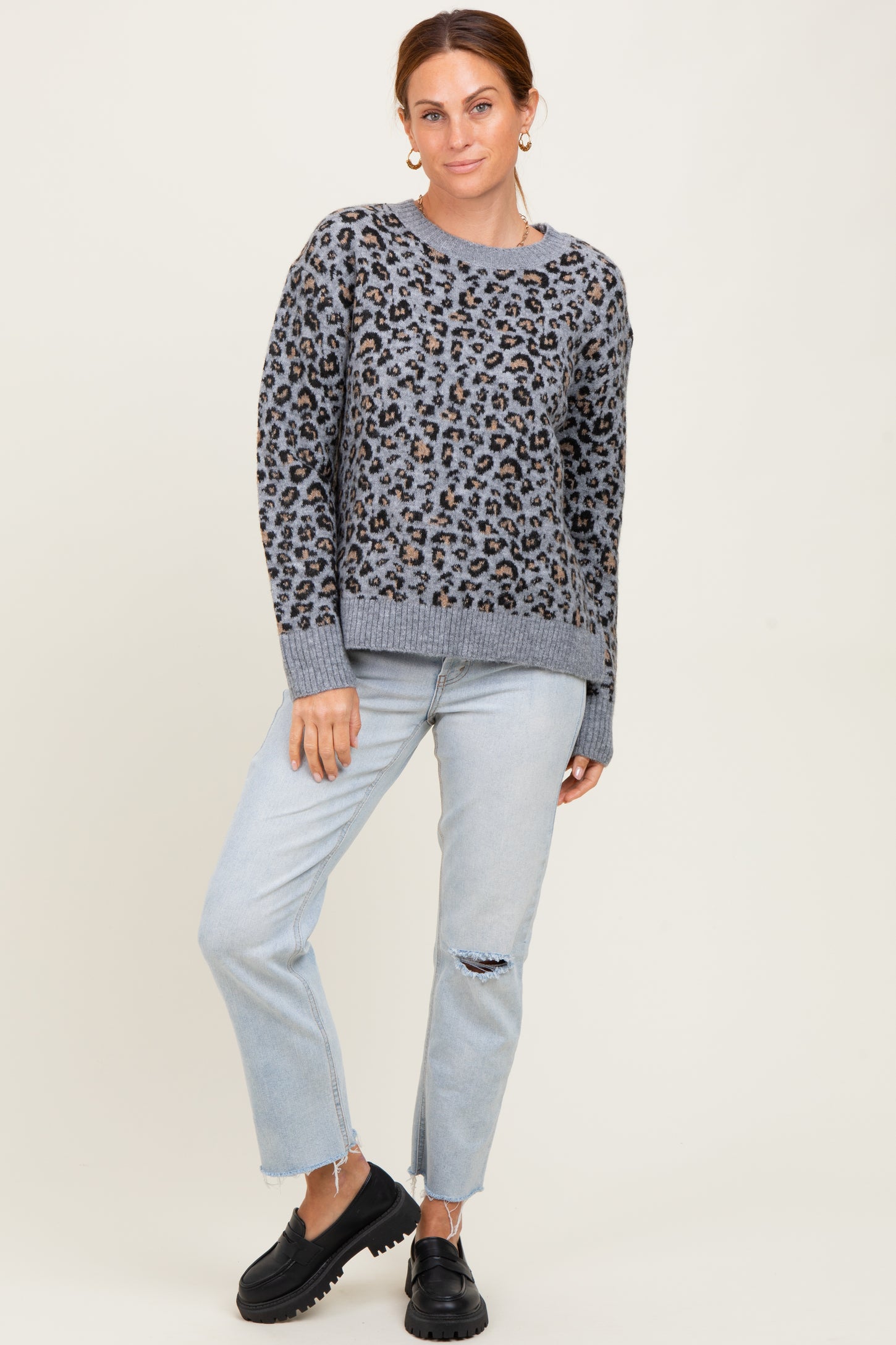 woman wearing a gray leopard print sweater and light blue distressed jeans, paired with black platform shoes