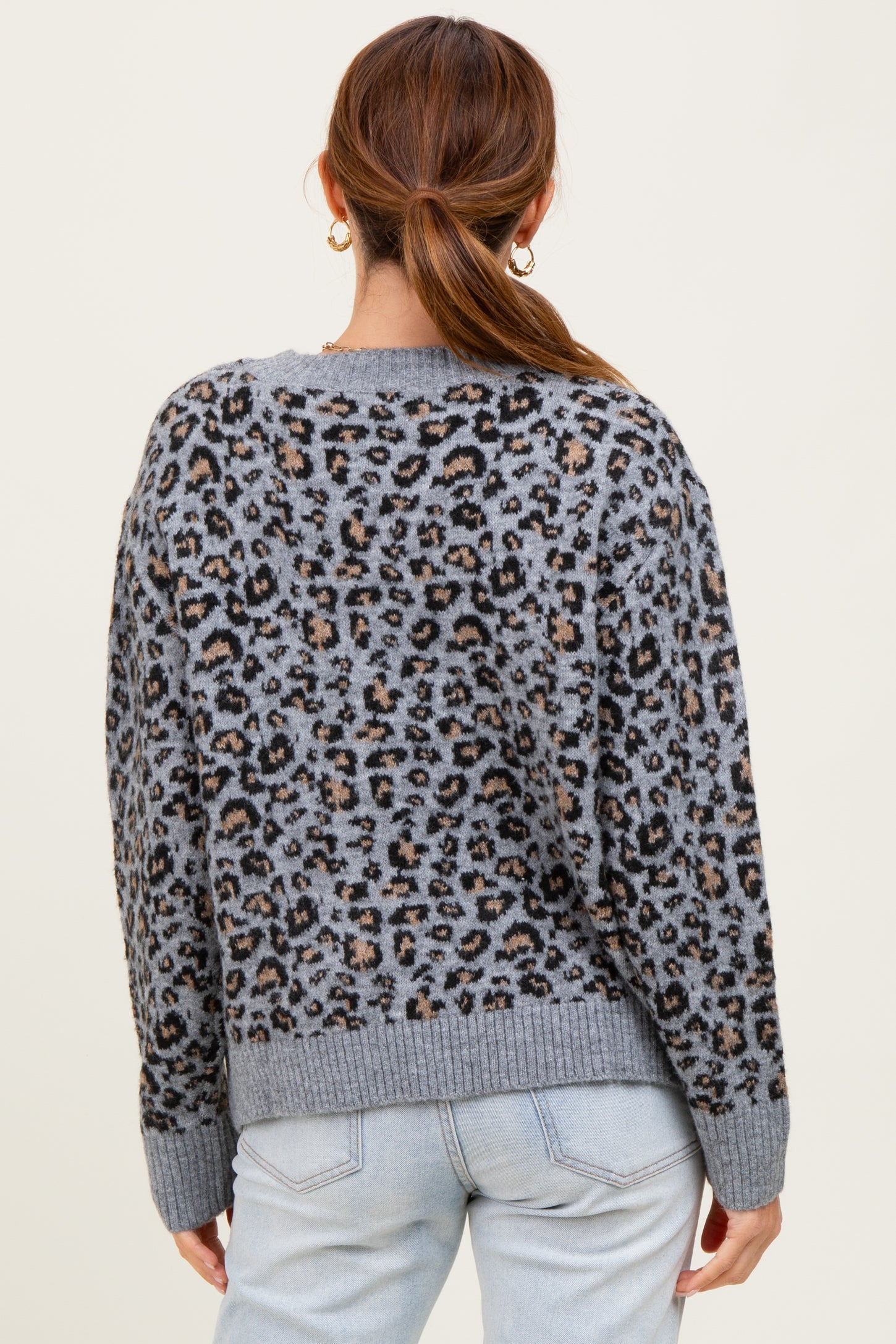 woman wearing a gray leopard print sweater with a relaxed fit and ribbed hem, seen from the back