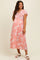 woman wearing a pink floral maternity maxi dress with flutter sleeves and a gathered waist, showing her baby bump