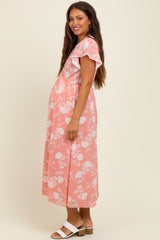 woman wearing a pink floral maternity maxi dress with flutter sleeves and a visible baby bump