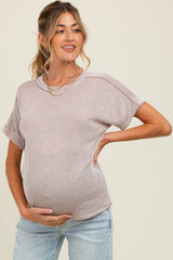 woman wearing a striped short sleeve maternity top and holding her baby bump
