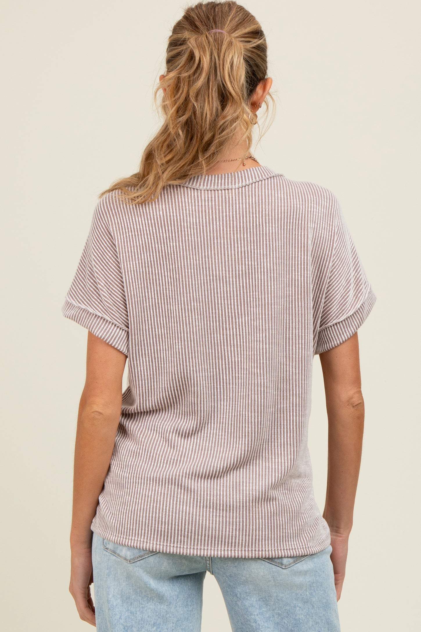 woman wearing a light brown striped maternity top, showing the back view with short sleeves and relaxed fit