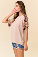 woman wearing a beige ribbed top with leopard print sleeves and distressed denim shorts