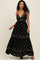 woman wearing a black floral maxi dress with a plunging neckline and cut-out detail, standing against a light background