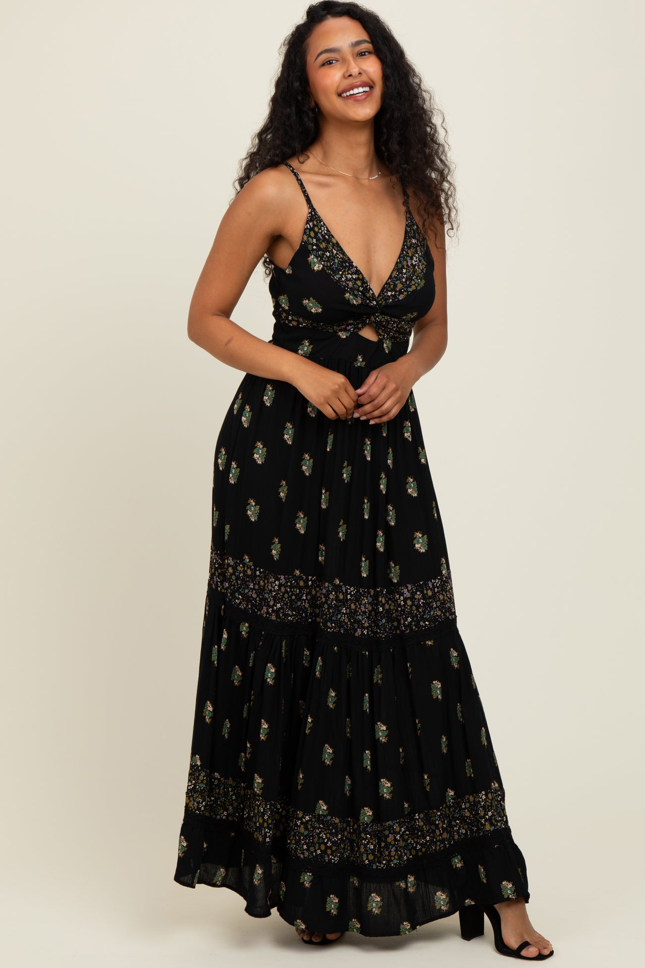 woman wearing a black floral maxi dress with a deep V-neck and tie front detail, smiling with curly hair