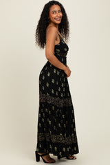 woman wearing a black floral maxi dress with a fitted bodice and tiered skirt, standing against a neutral background