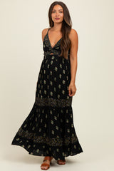woman wearing a black floral maternity maxi dress with a plunging neckline and a flowy skirt, showing her baby bump