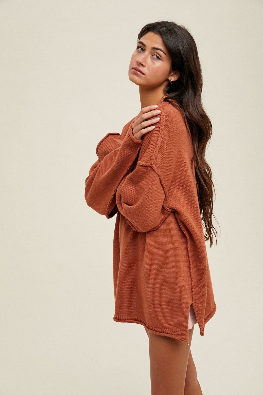 woman wearing an oversized rust-colored sweater with a relaxed fit and side slits