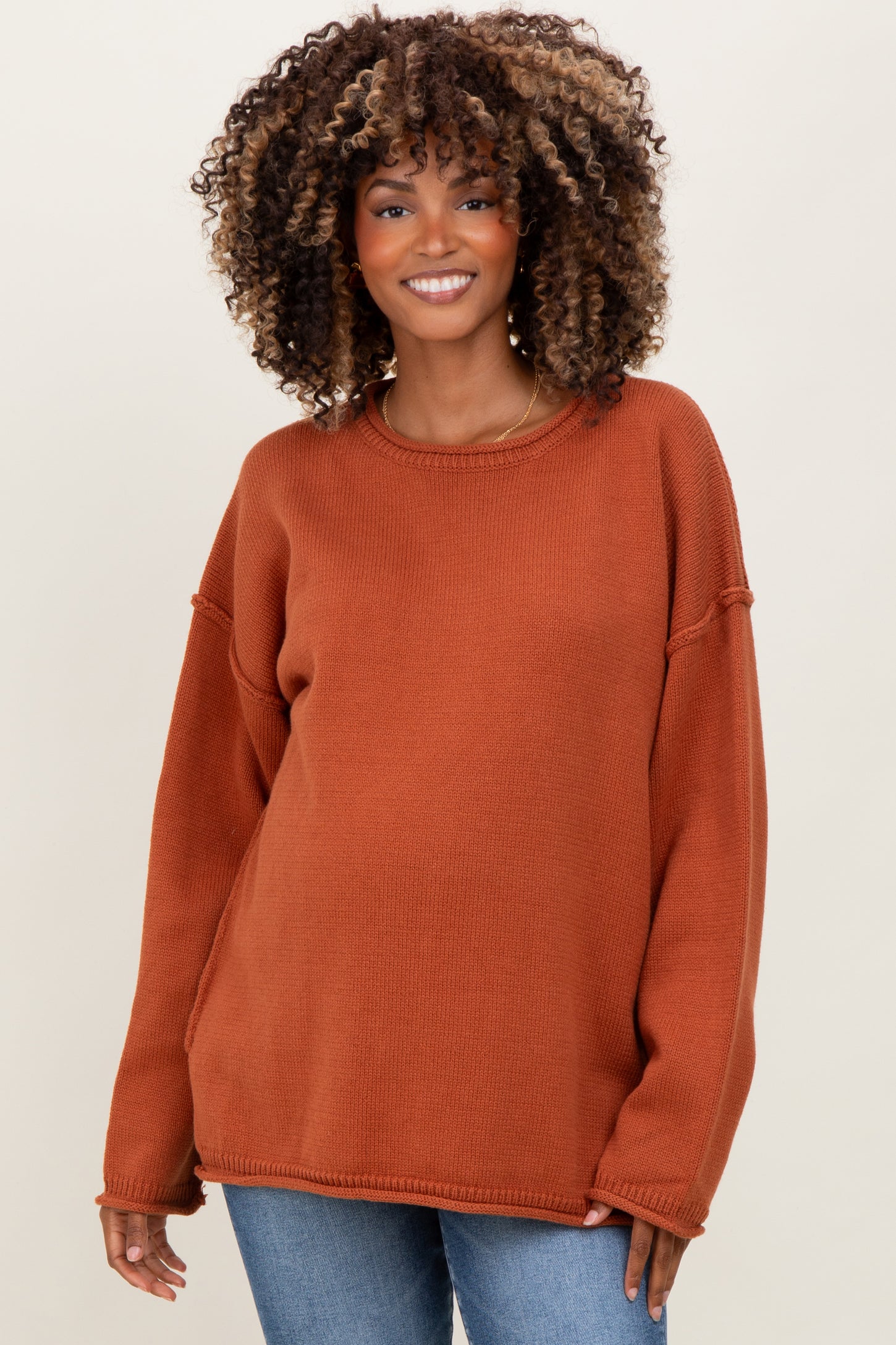 woman wearing a rust oversized maternity sweater with a relaxed fit and rounded neckline, showcasing her baby bump