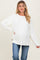 woman wearing a white oversized maternity sweater with relaxed sleeves and a visible baby bump