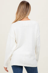 woman wearing a cream oversized maternity sweater with a relaxed fit and long sleeves, viewed from the back