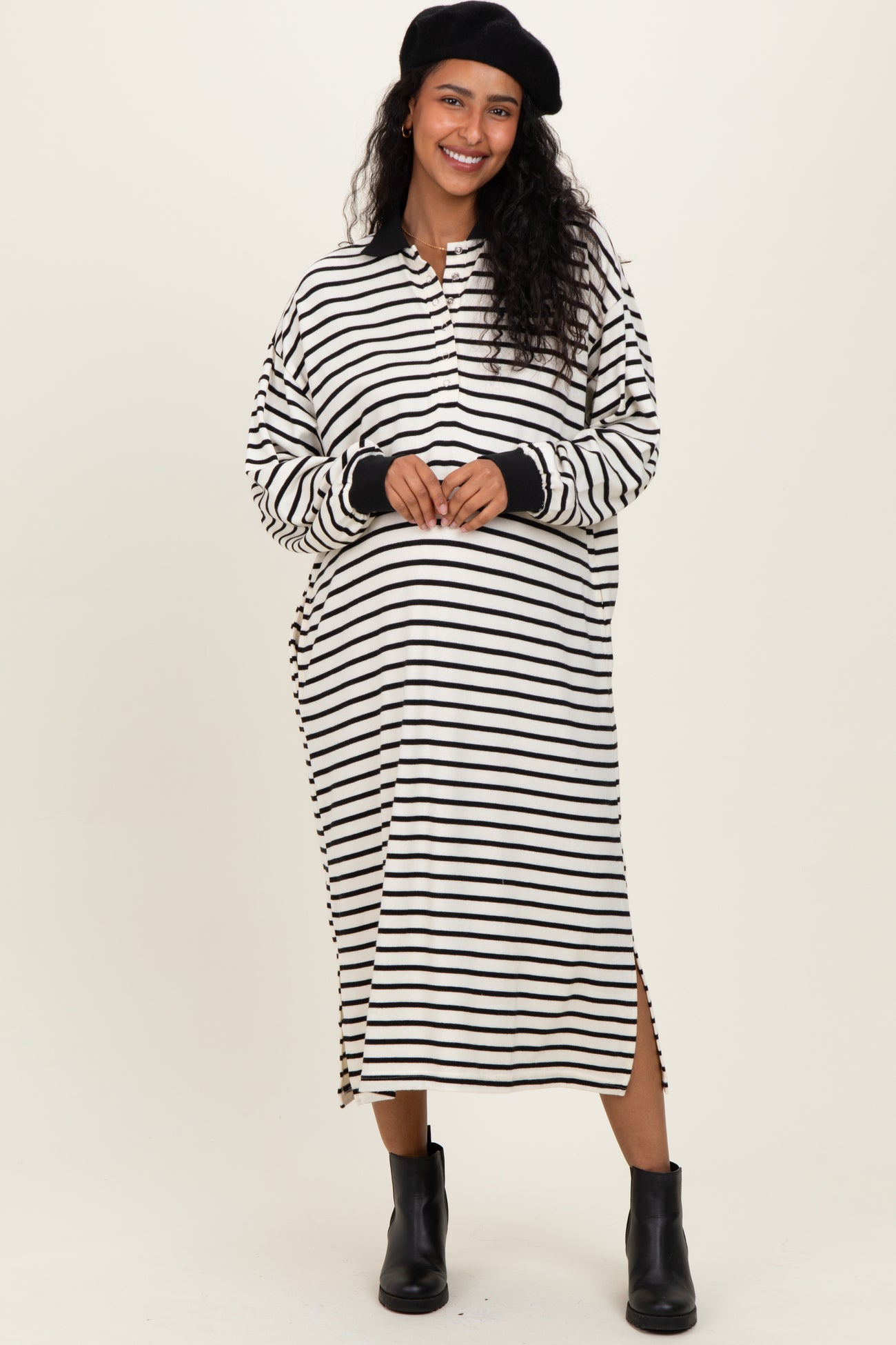 woman wearing a black and white striped maternity dress with side slits and long sleeves, showcasing her baby bump