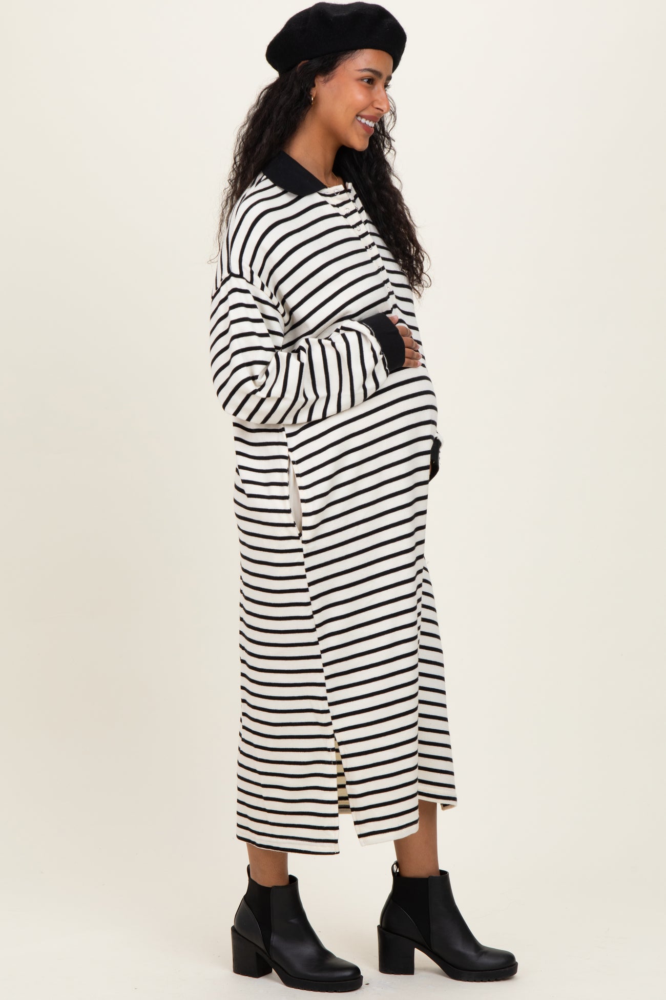 woman wearing a black and white striped maternity dress with a relaxed fit and side slits, showing her baby bump