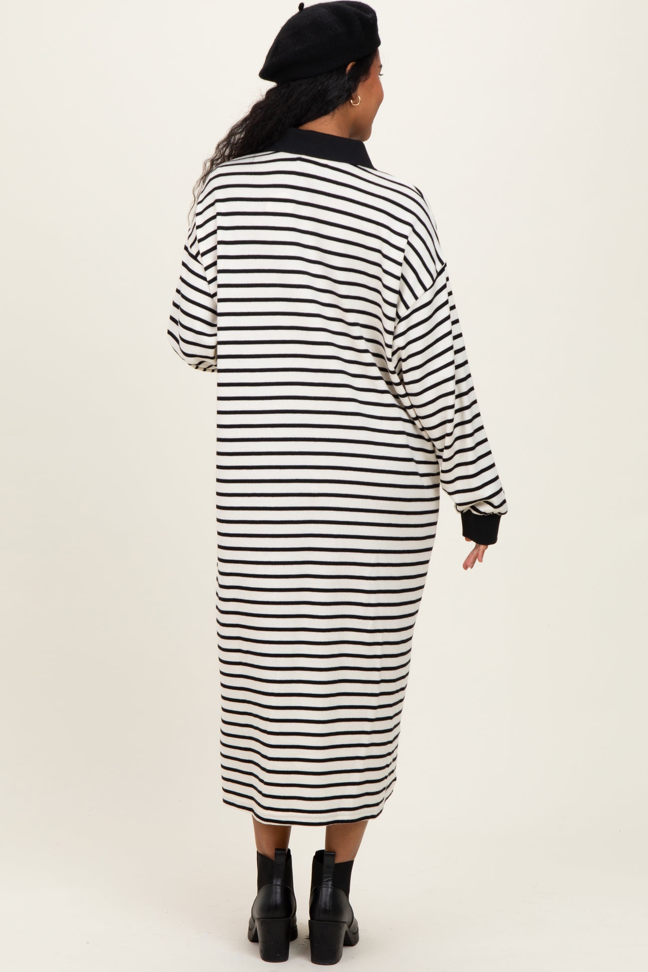 woman wearing a black and white striped maternity dress that falls to the mid-calf, shown from the back