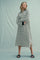 woman wearing a black and white striped long sleeve midi dress with side slits and black cuffs