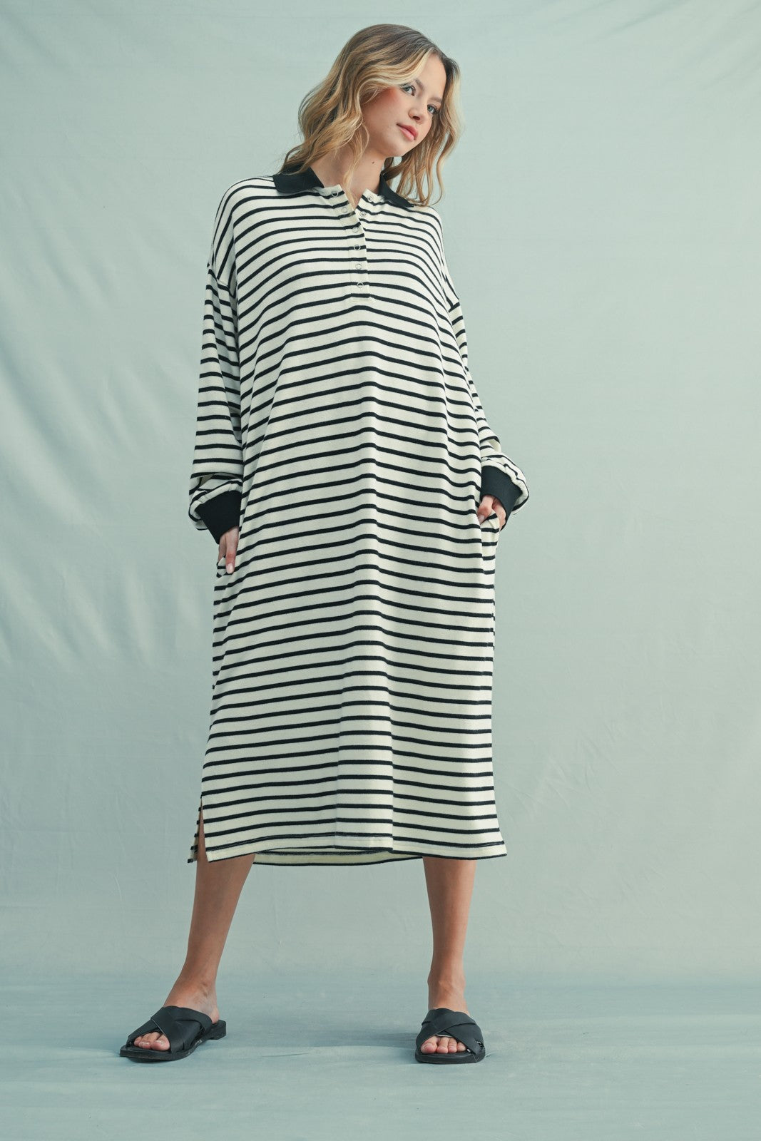 woman wearing a black and white striped long sleeve oversized dress with side pockets and a collar