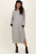 woman wearing a black and white striped maternity dress with long sleeves and side slits, styled with a black beret