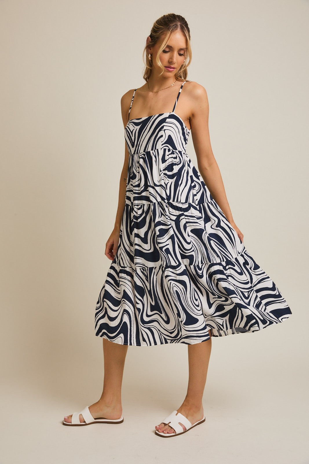 woman wearing a navy and white abstract print tiered midi dress with spaghetti straps and sandals