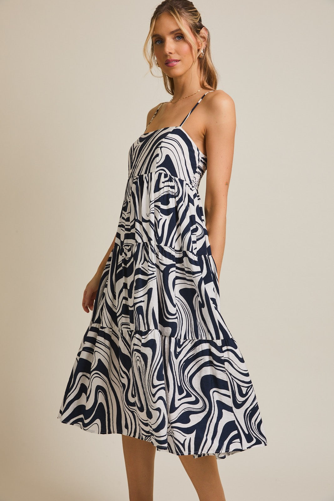 woman wearing a navy and white abstract print tiered midi dress with spaghetti straps