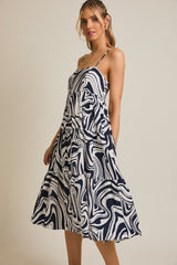 woman wearing a navy and white abstract print tiered midi dress with spaghetti straps