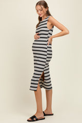 woman wearing a black and white striped midi maternity dress with a side slit and holding her baby bump
