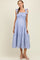 woman wearing a light blue and white striped maternity maxi dress with tie straps and a tiered skirt, showing her baby bump