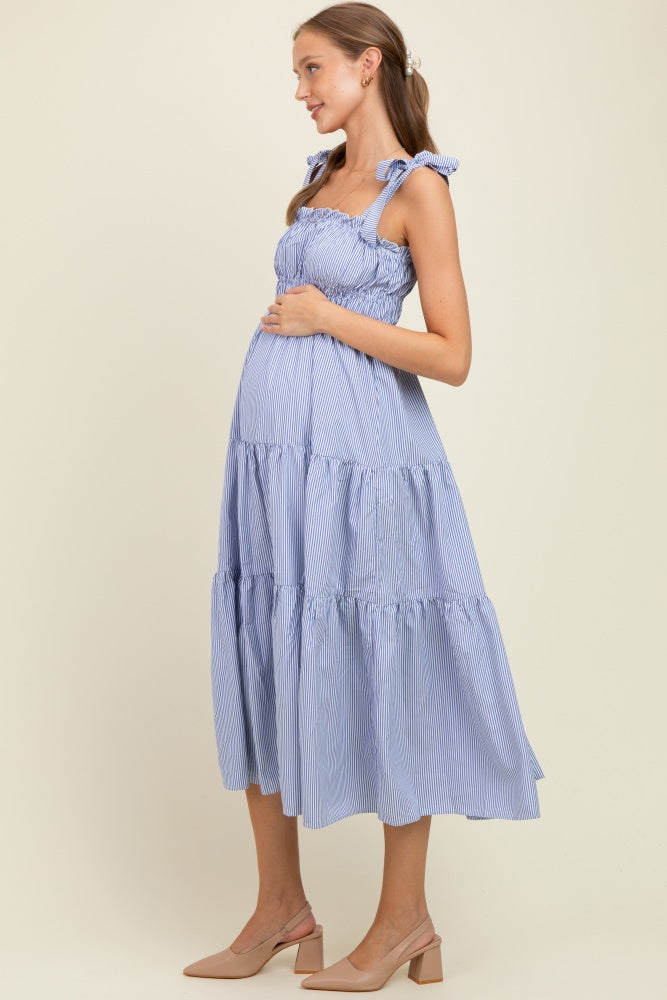 woman wearing a blue and white striped maternity maxi dress with ruffle straps and a visible baby bump