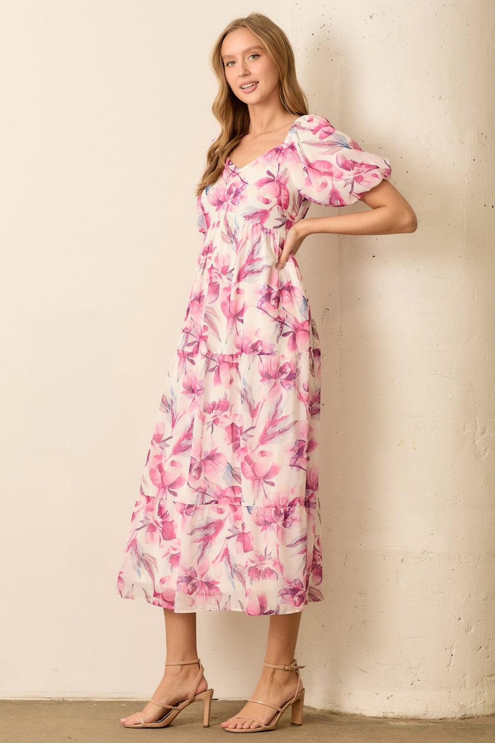 woman wearing a floral pink midi dress with puff sleeves and a fitted bodice
