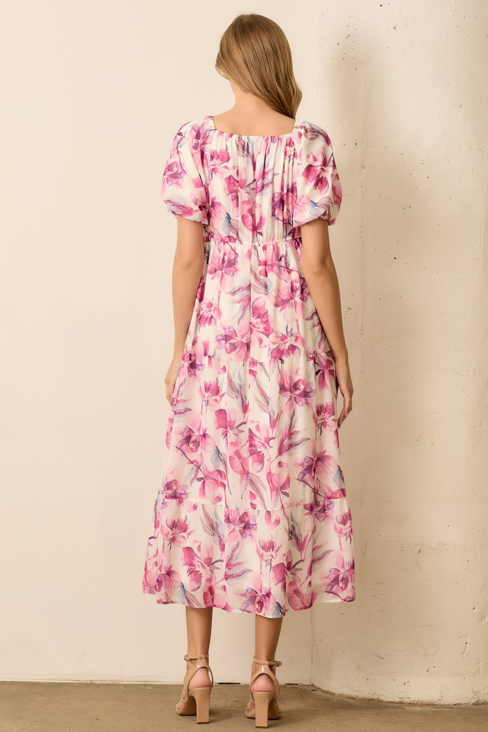 woman wearing a floral midi dress with puff sleeves and a fitted waist, seen from the back