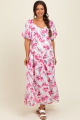 woman wearing a floral pink maternity maxi dress with short puff sleeves and a flowing skirt, showing her baby bump