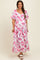 woman wearing a floral pink maternity maxi dress with short puff sleeves and a flowing skirt, showing her baby bump
