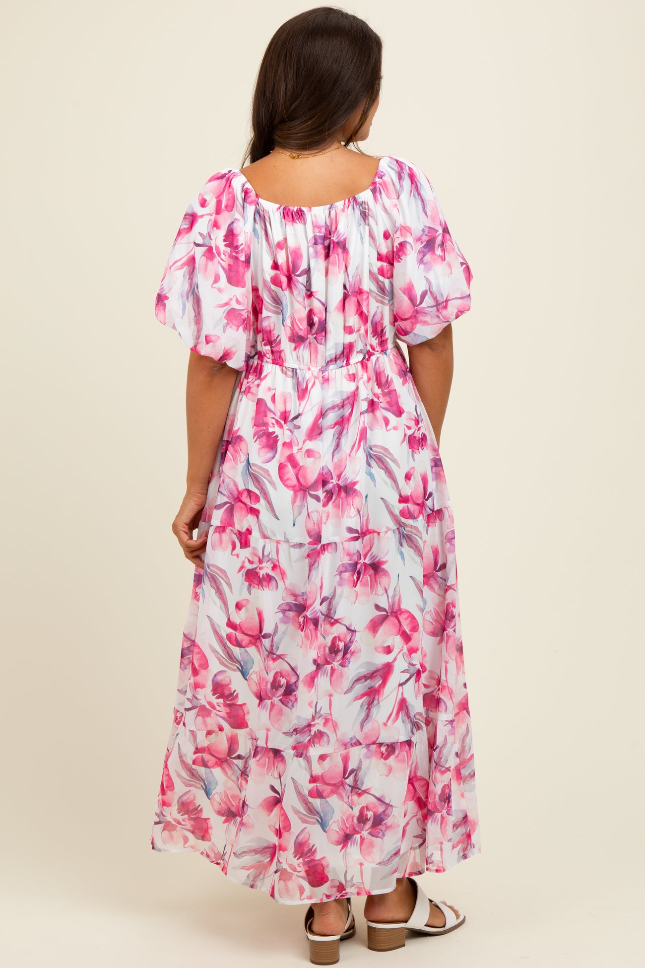 woman wearing a floral pink maxi maternity dress with puff sleeves and a smocked back, showing a baby bump